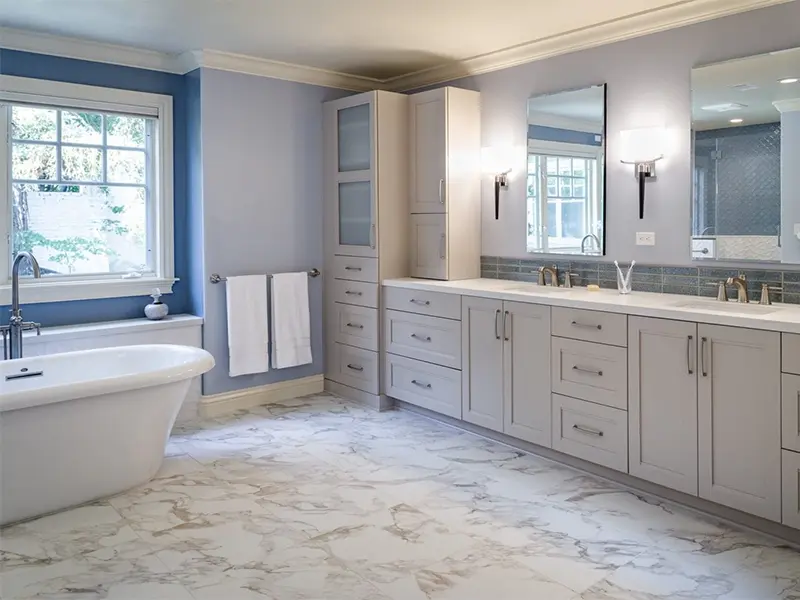 Spacious bathroom with a freestanding tub, double vanity, and marble-patterned floor tiles.