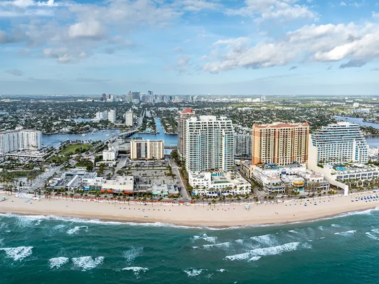 Aerial view of a beachfront cityscape with high-rise buildings and ocean waves.