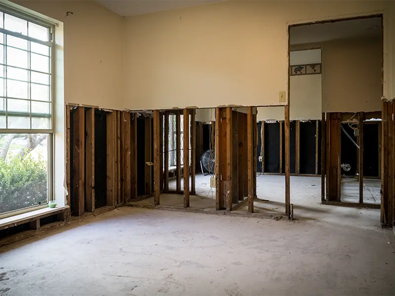 Interior of a room with drywall removed halfway, exposing wooden studs and insulation.